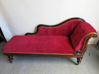 Chaise Lounge with Wooden Scroll Top Frame. Upholstered in Red Velour with Gold Braiding Detail on Metal Castors. Size H80 x W180 x D65cm. NOTE: missing 1 Castor.