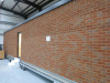 15.3m x 2.62m - Ex-Show Room Modular Housing Display Unit with Brick Front Finish, 2 Rendered Ends with Finish Required Top & Rear. Unit Sits on 2 x Sets of 6 Wheeled Galvanised Mobile Frames (7 x 3m). Fitted with Kitchen, Toilet, Shower room & Bedroom, A - 8