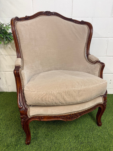 A Louis XV Style Walnut Bergere Armchair in Neutral Coloured Velvet Effect Upholstery. NOTE: requires minor repairs to backrest where fabric separated from frame.