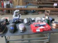 Table Containing a Quantity of Welding Accessories Including: 8 x Welding Masks, Respirator, 2 x Reels of Mig Welding Wire, Oxy/Acetylene Bottle Gauge, Cutting Torch, Assorted Arc Welding Sticks & Filters (As Viewed)